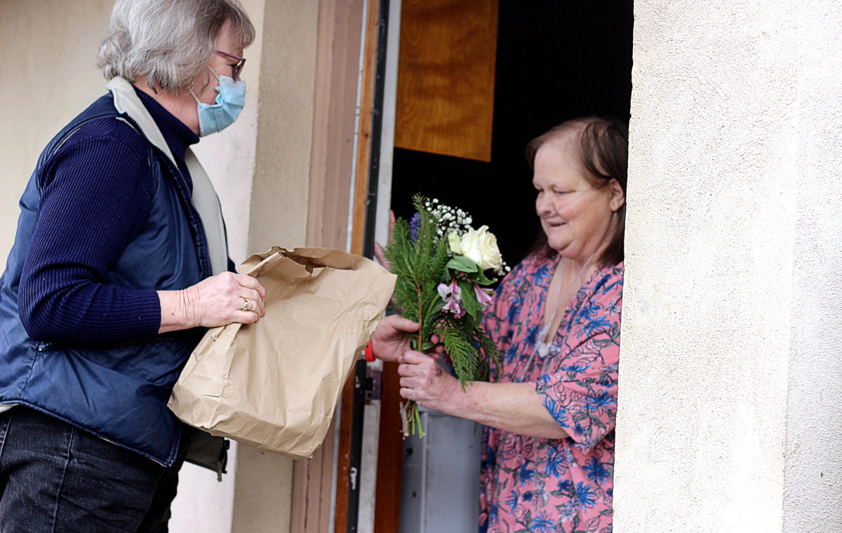 Volunteer delivers meal and flowers to a Meals on Wheels recipient