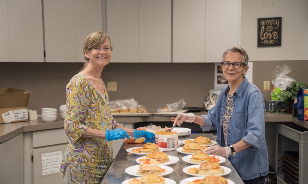 two volunteers preparing meals at the sisters meal site