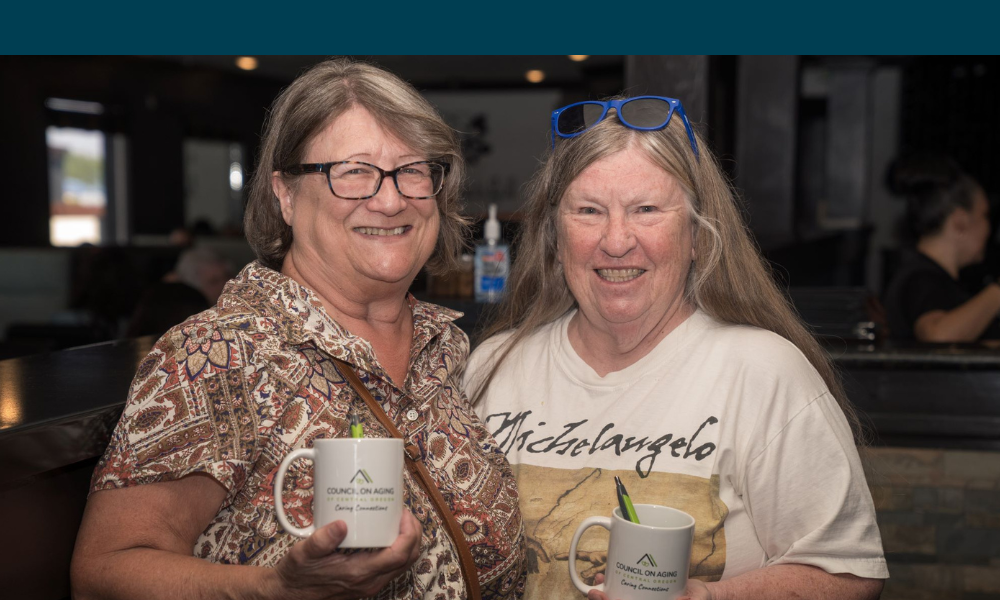 Two caring connections participants at an event holding mugs