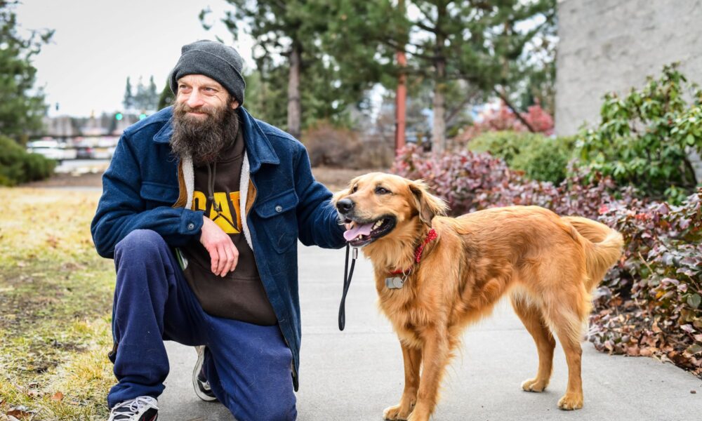 Man kneeling next to his golden retriever